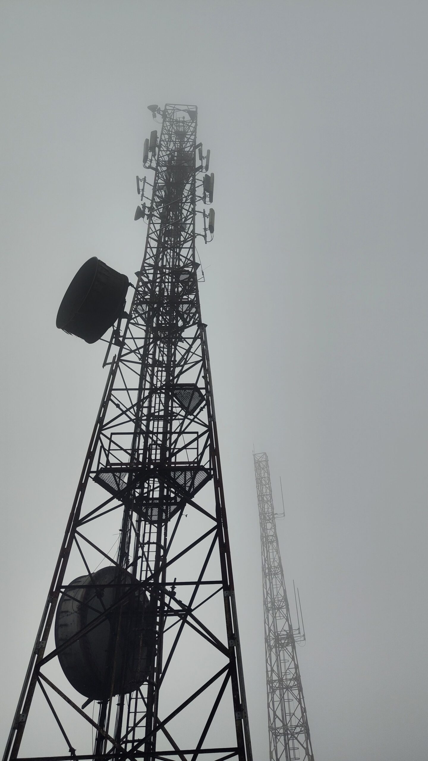 Menara BTS dengan beberapa antena di puncak dalam cuaca berkabut